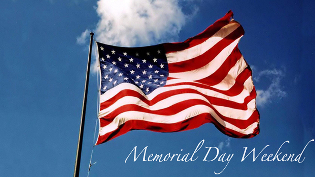 Image of an American flag flying high with a blue sky and cloud behind it.  And the words saying "Memorial Day Weekend" at the bottom.